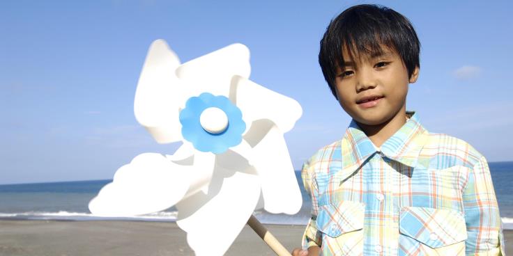 Boy holding pinwheel at beach